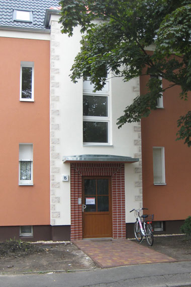 kleines Bild - Eingang 15 Brüder-Lang-Straße 11-13-15 in Bitterfeld hat 16 Wohnungen, 1 + 2 RWE, 33 - 52 m<sup>2</sup>, Fernwärme, Stellplätze möglich. Nebengelass in Verbinderbauten bzw. Dachgeschoss. Viel Grün und Gartennutzung möglich. Mehrere Garagenkomplexe im Wohngebiet vorhanden.